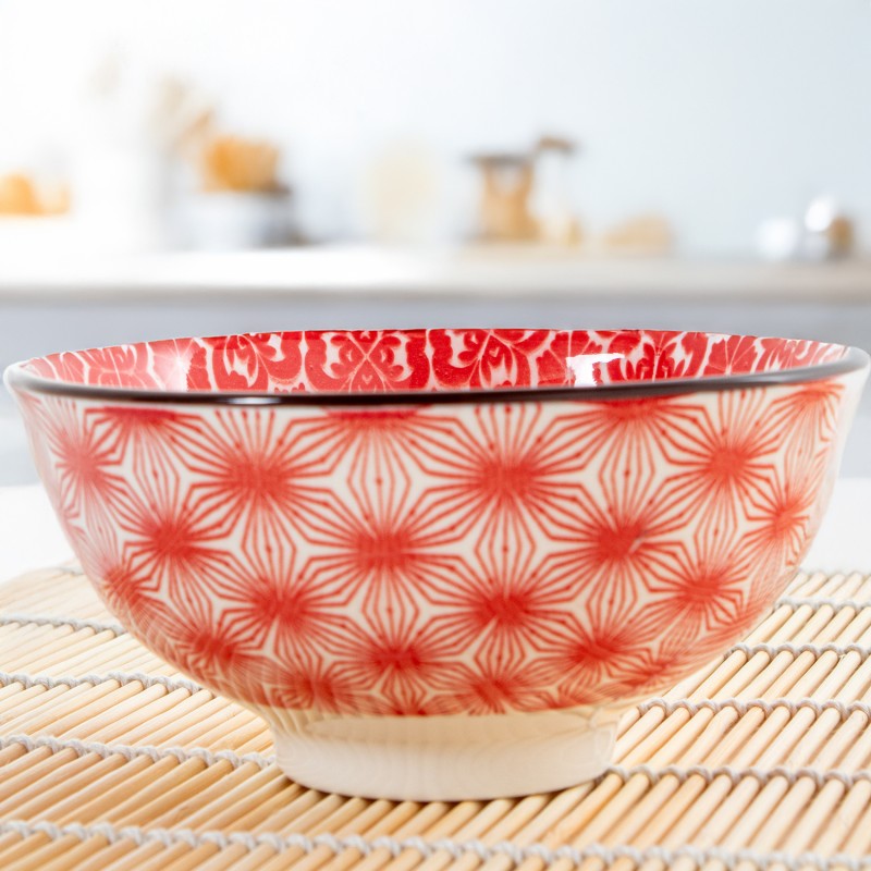 Cuenco de porcelana con diseño floral rojo en ambiente de cocina, sobre salvamanteles de bambú