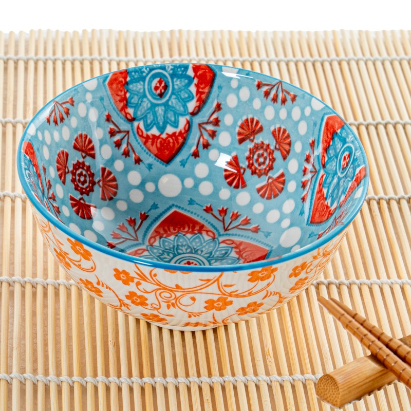 Primer plano del cuenco de porcelana mostrando el detalle del diseño floral azul y naranja de estilo oriental y el acabado brillante
