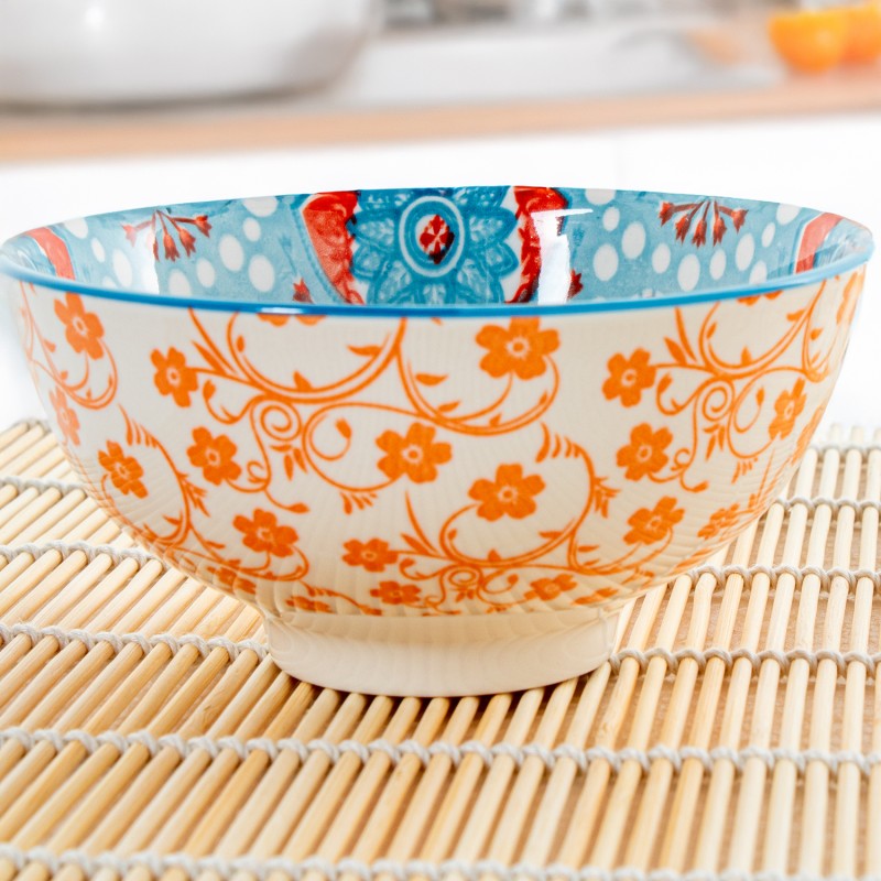 Cuenco de porcelana con diseño floral azul y naranja de estilo oriental en ambiente de cocina, sobre salvamanteles de bambú