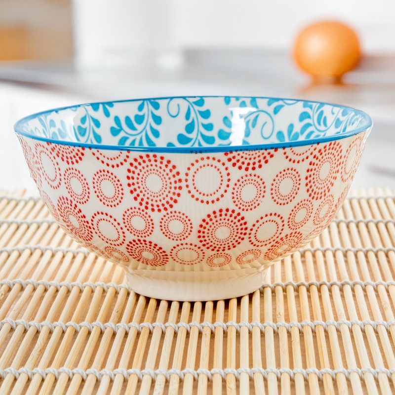 Detalle del cuenco de porcelana mostrando el interior con diseño floral azul y el exterior con patrón de círculos rojos
