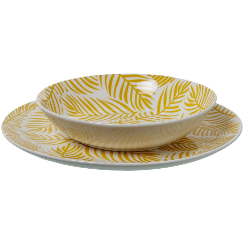 Tazón de porcelana amarilla con hojas sobre plato llano a juego, vista frontal sobre fondo blanco