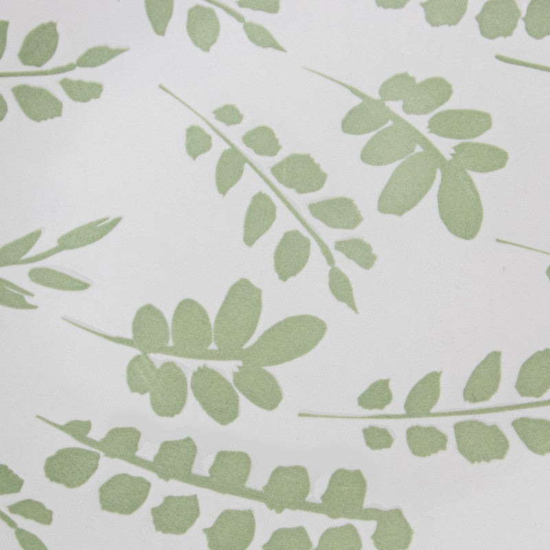 Primer plano macro del diseño de hojas verdes pintado a mano sobre la porcelana blanca de la vajilla