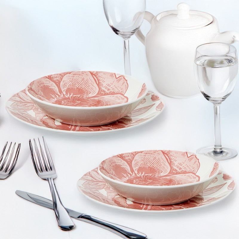 Vajilla de porcelana con flores rosas dispuesta en mesa elegante junto a copas, cubiertos y tetera