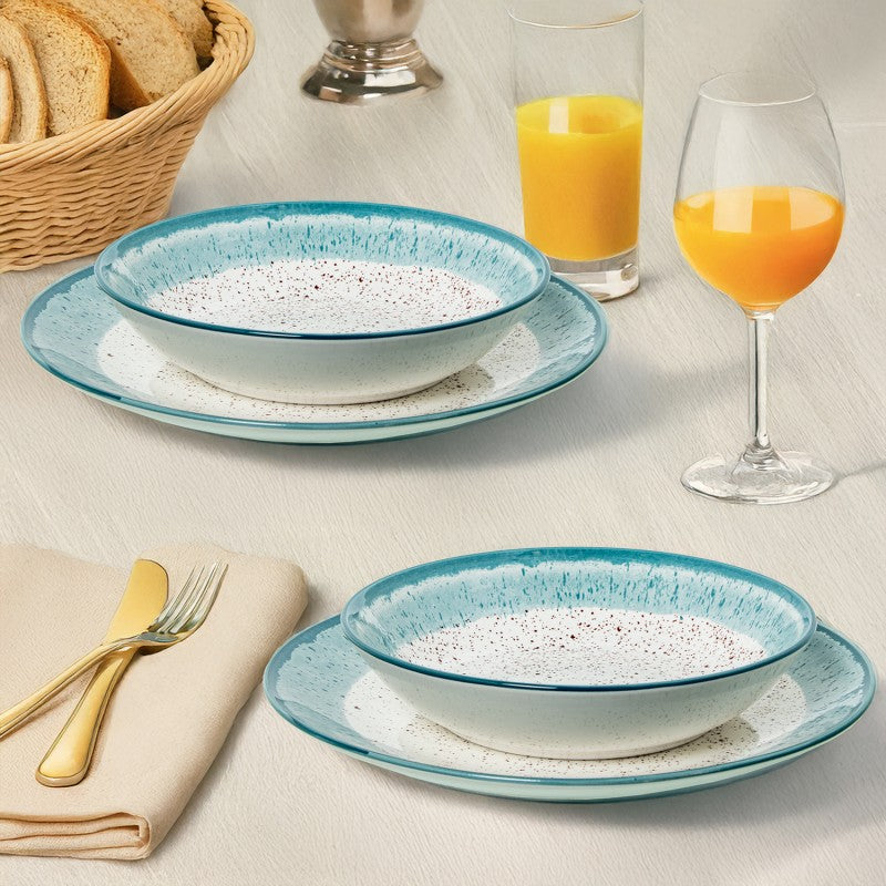 Platos hondos de porcelana con borde azul moteado servidos en mesa junto a pan y zumo de naranja