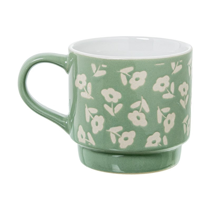 Detalle de un mug de cerámica verde con estampado floral blanco y asa