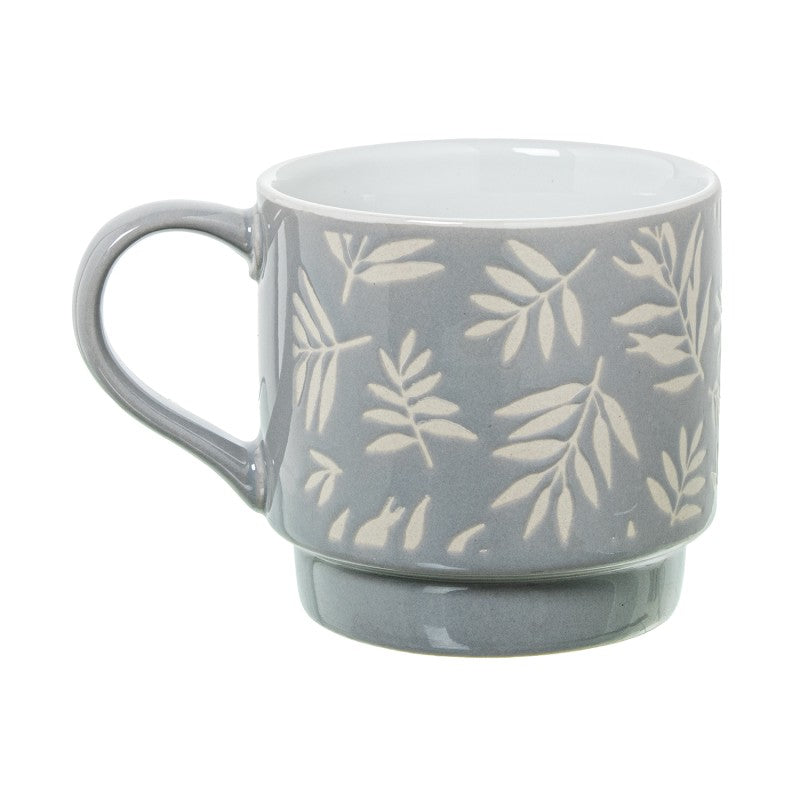 Detalle de un mug de cerámica azul con estampado de hojas blancas y asa