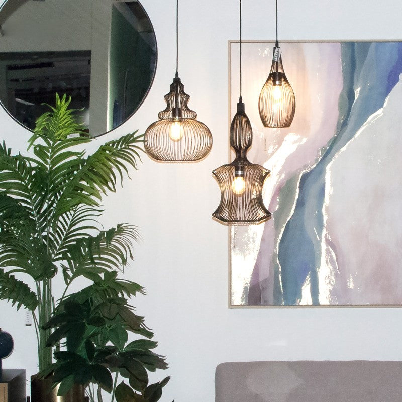 Lámparas de techo de metal negro con forma de gota encendidas decorando un salón con plantas y cuadro