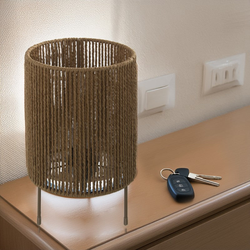 Lámpara de sobremesa de mimbre encendida sobre mueble de recibidor junto a llaves