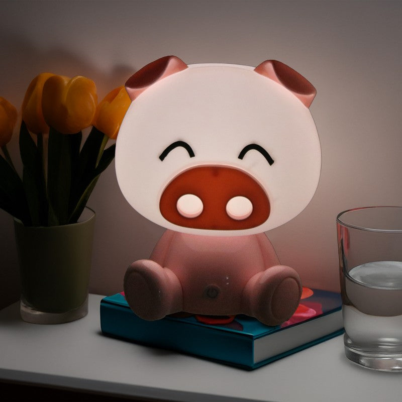 Lámpara cerdito encendida decorando una mesita junto a tulipanes