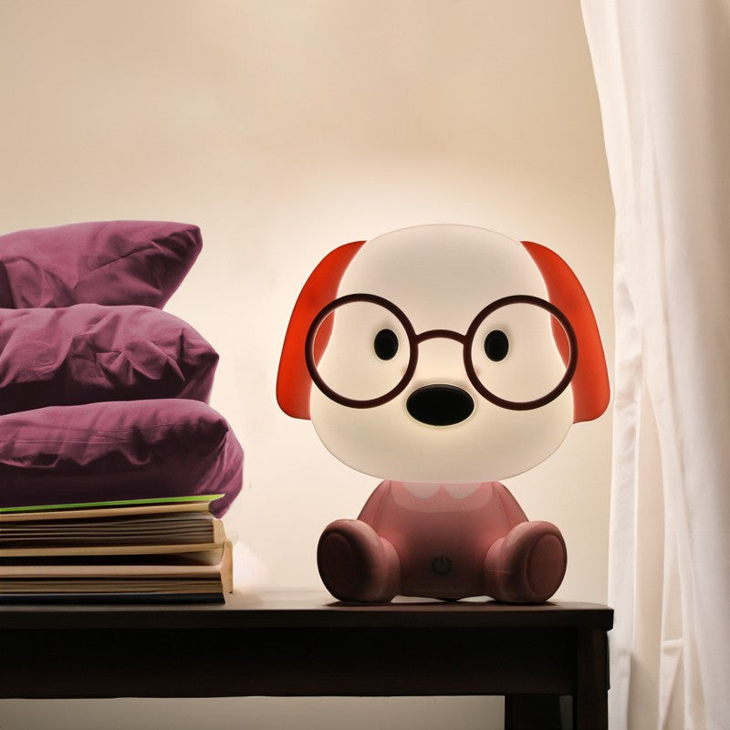 Lámpara perrito rosa encendida decorando una mesita de noche junto a la cama