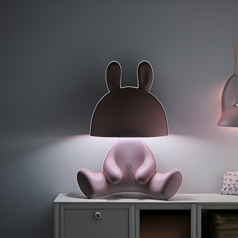 Lámpara conejo rosa encendida decorando una cómoda junto a la ventana