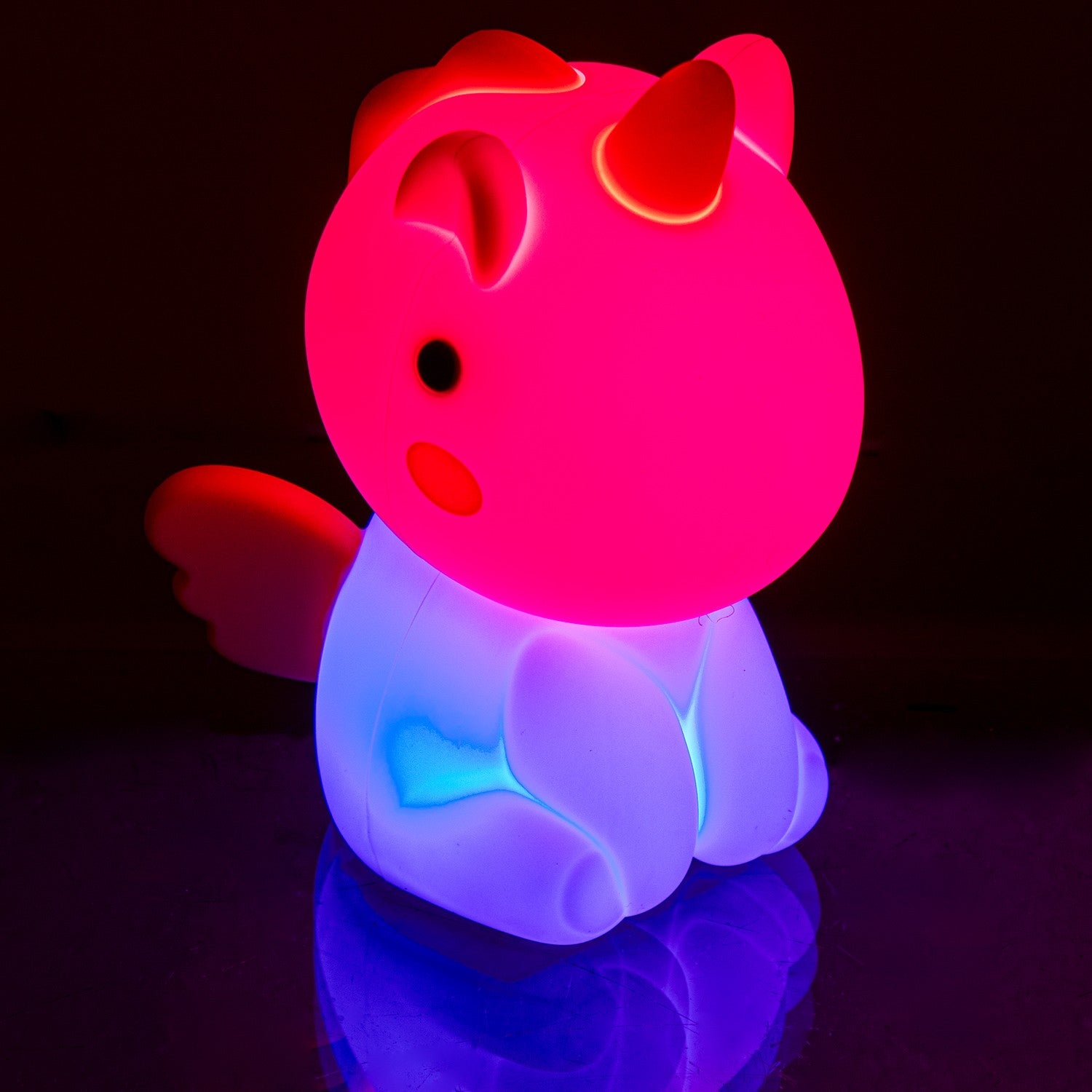 Luz nocturna de unicornio encendida en modo multicolor, con tonos rosa y azul, en ambiente oscuro