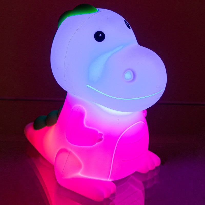 Luz nocturna de dinosaurio encendida en tonos azul y rosa en ambiente oscuro