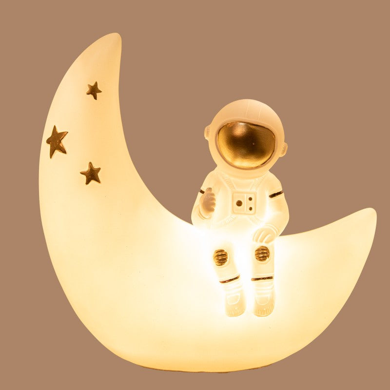 Lámpara LED encendida con luz cálida iluminando la figura de astronauta sobre la luna