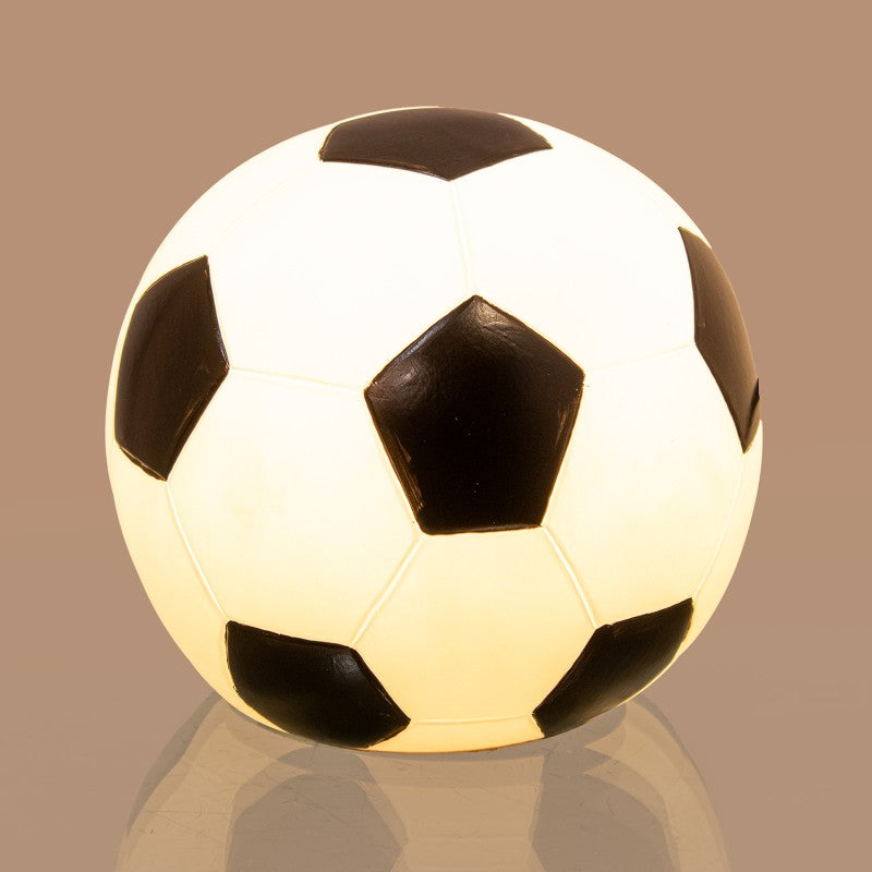 Lámpara LED encendida con forma de balón de fútbol, luz cálida iluminando el interior