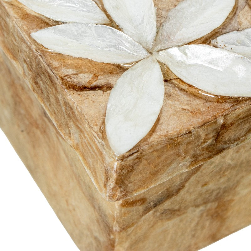 Detalle en primer plano de la flor de nácar tallada en relieve sobre la esquina de la caja