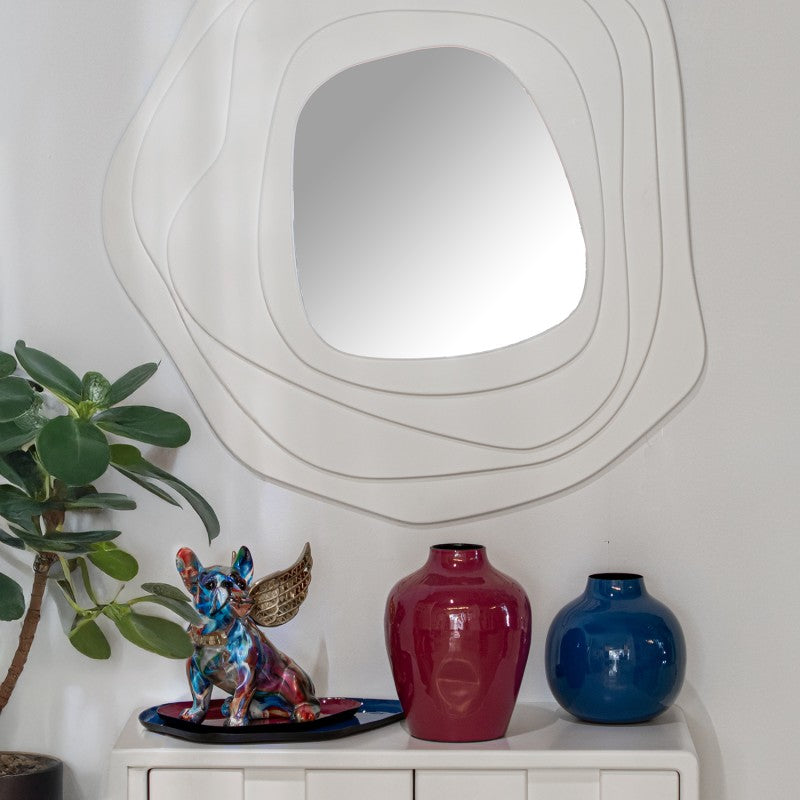 Espejo de pared blanco de diseño orgánico decorando un recibidor sobre un mueble con jarrones