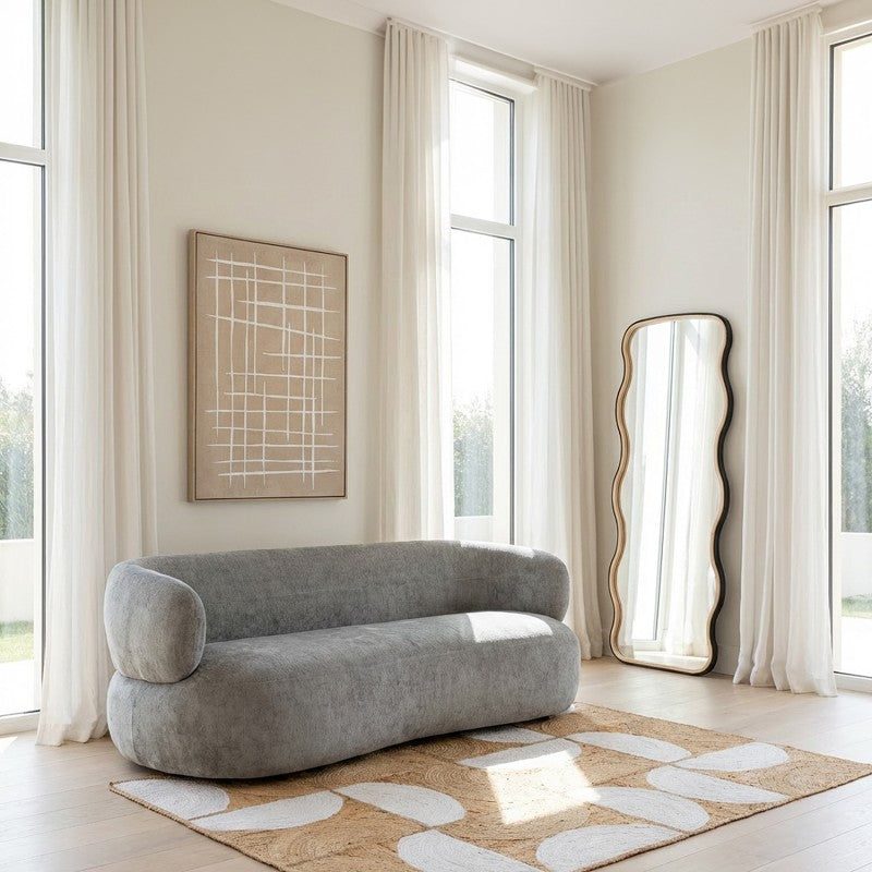 Espejo ondulado de madera decorando un salón luminoso junto a sofá gris y ventanales