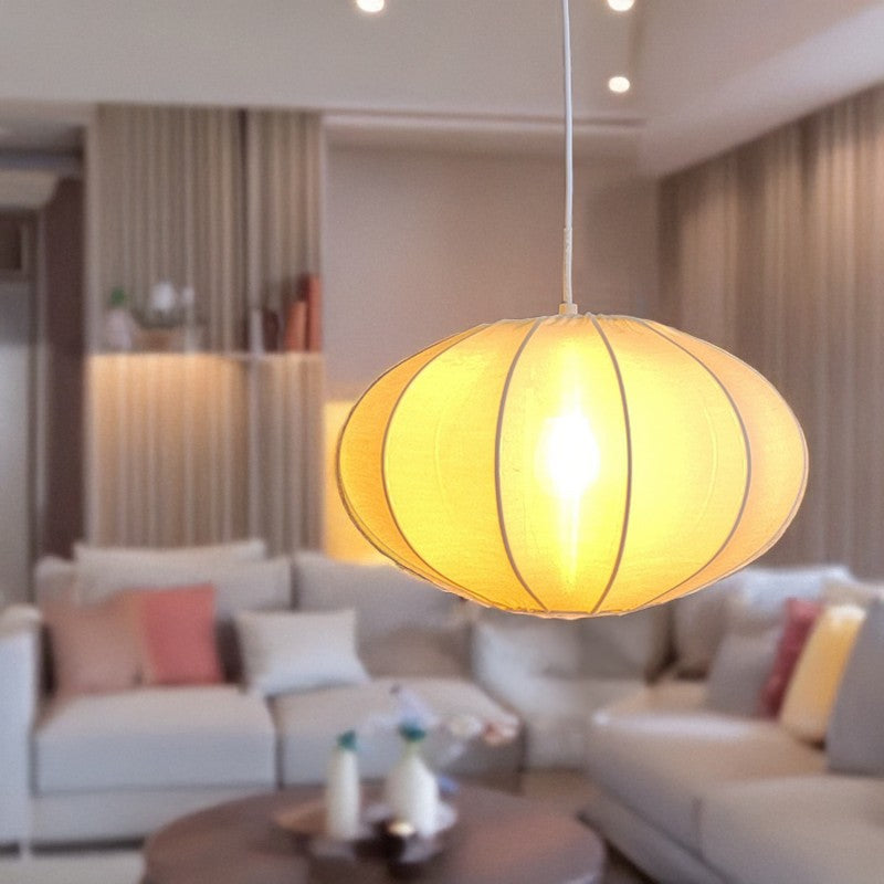 Lámpara de techo con pantalla de algodón blanco encendida, iluminando un salón con luz cálida