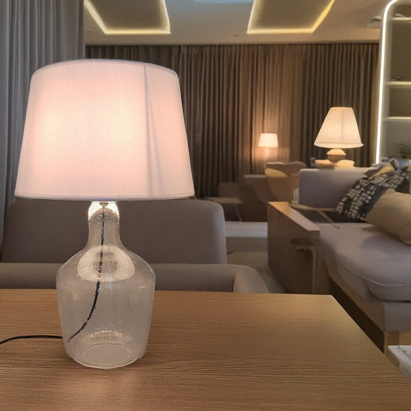Lámpara de sobremesa con base de cristal encendida en un salón elegante